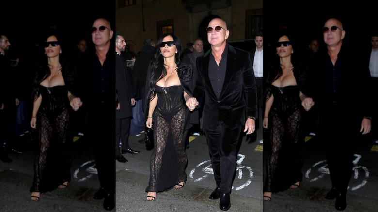 Lauren Sánchez Bezos in a black lace dress walking hand-in-hand with Jeff Bezos
