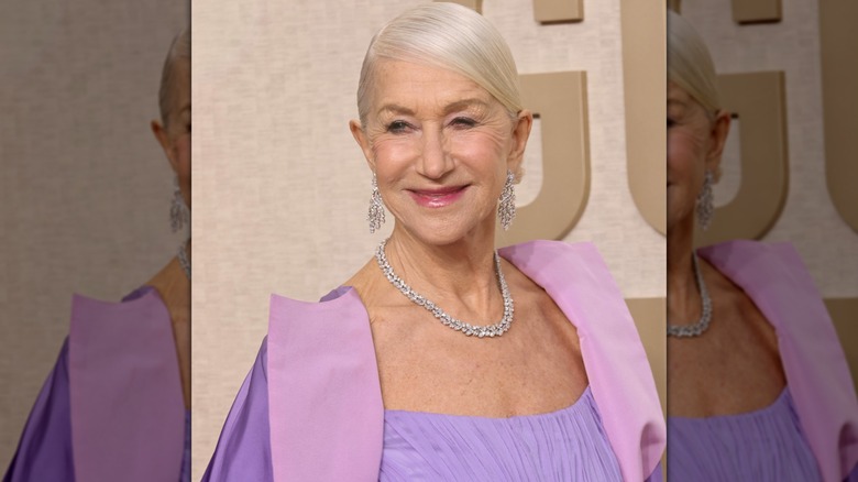 Close-up of Helen Mirren at the Golden Globe Awards, smiling while wearing a glossy, pink lip color