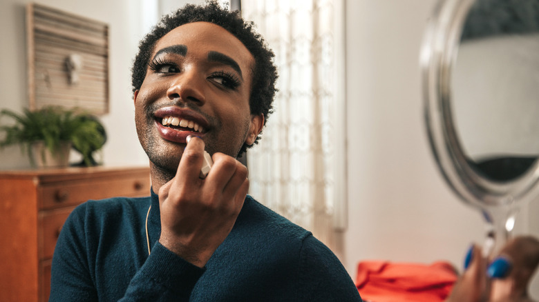 model applying lipstick in mirror