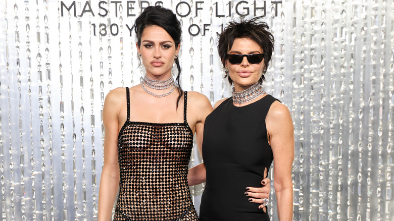 Amelia Hamlin wears a sheer black dress next to Lisa Rinna wearing sunglasses