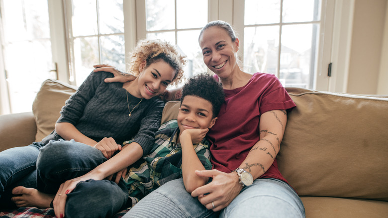 Same-sex couple sits on couch with their child between them