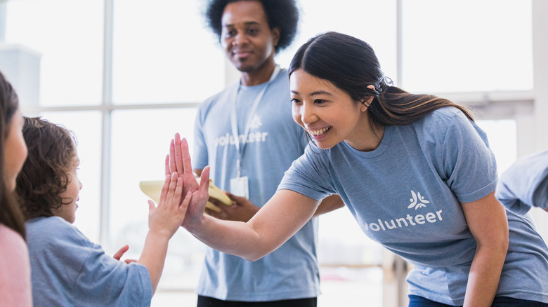 Woman wearing shirt that says volunteer high-fives a child