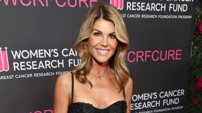 Lori Loughlin smiles wearing a strappy black dress