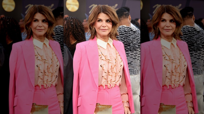 Lori Loughlin smiles wearing a ruffled blouse and a pink blazer