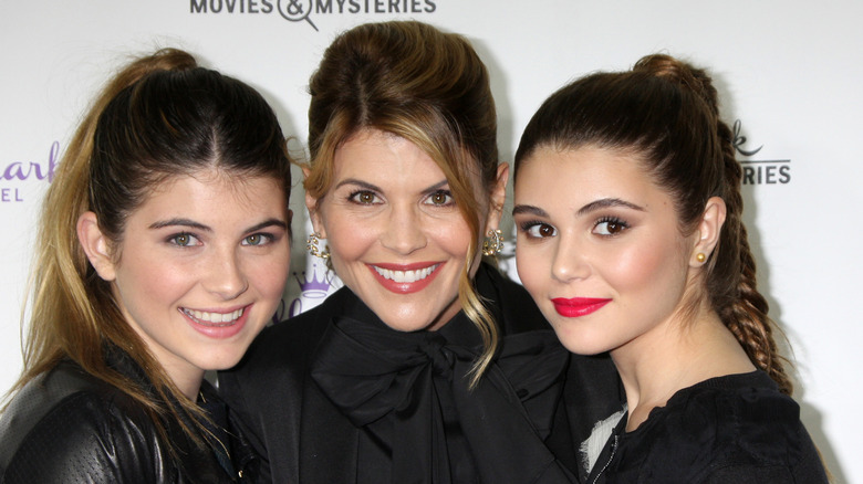 Lori Loughlin wearing a black bowtie top and updo with blonde highlights