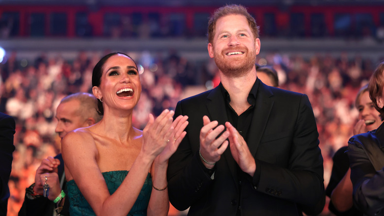 Prince Harry and Meghan Markle clapping and smiling at the Invictus Games