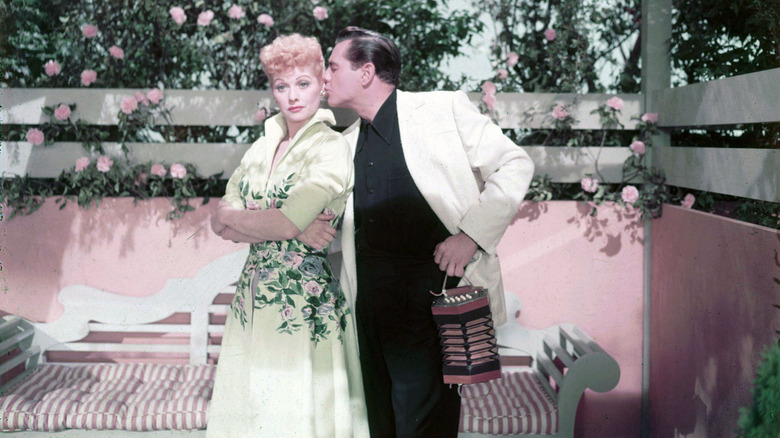Lucille Ball being kissed on the cheek by Desi Arnaz in a rose garden