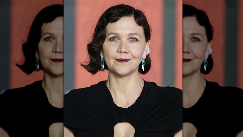 Maggie Gyllenhaal in a black dress with emerald earrings at an event