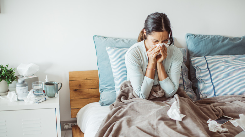 woman blowing nose in bed