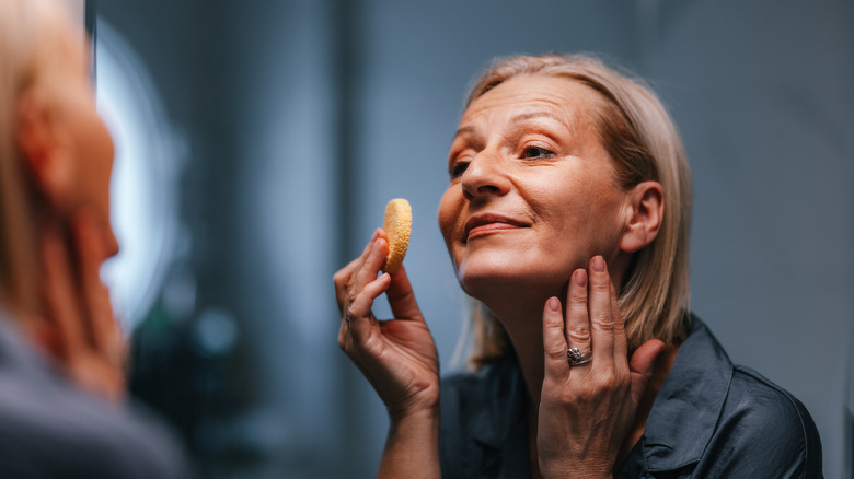 Older woman applying makeup with a sponge