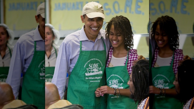 Malia Obama, wearing her hair in a twisted style, smiling with her father at a volunteer event