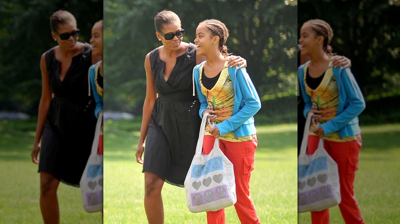 Malia Obama, wearing her hair styled in cornrows, smiling while walking with her mom in 2009