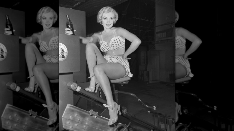 Marilyn Monroe wearing a polka-dotted bikini and holding a glass bottle of Coke on the set of "Love Nest"