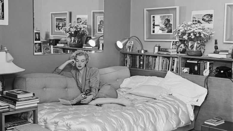 Marilyn Monroe laying on a bed and reading a book