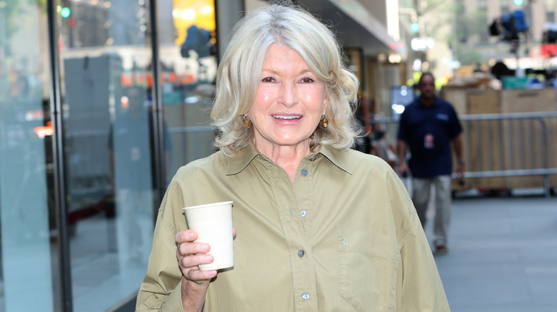 Martha Stewart posing with a wine glass sitting on a wooden bench