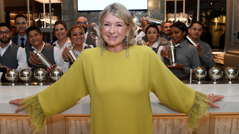 Martha Stewart in lime green posing with several waiters