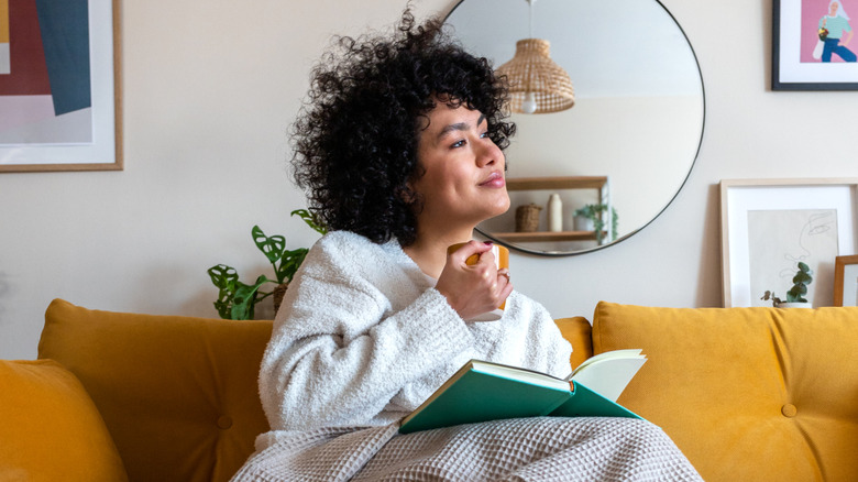 Woman reading on her couch with a mug in-hand