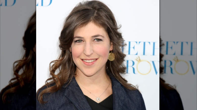 Mayim Bialik with her natural curls out wearing a black blazer