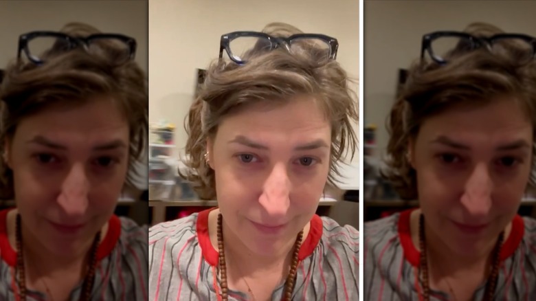 Mayim Bialik wearing glasses and peppered gray cropped hairstyle