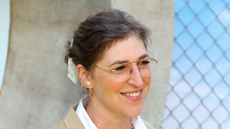 Mayim Bialik wearing glasses and brunette hair with slight graying