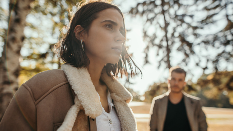 Woman in the park looking stressed with man behind her