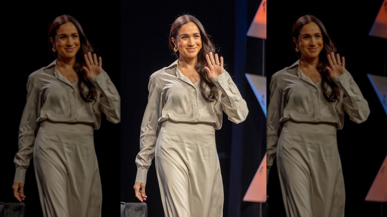 Meghan Markle waving in a loose green shirt and matching skirt