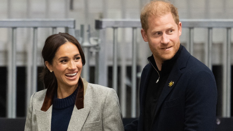 Prince Harry and Meghan Markle walking past metal fencing