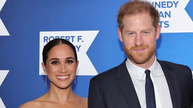Meghan Markle and Prince Harry smiling on the red carpet in 2022