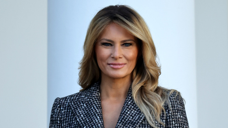 Melania Trump with long blond hair in a black and white coat at an event