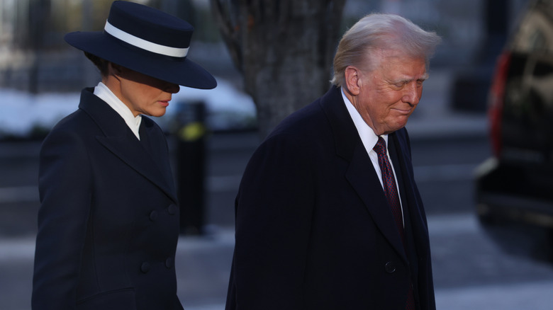 Melania Trump in a blue and white hat with Donald Trump in a black jacket