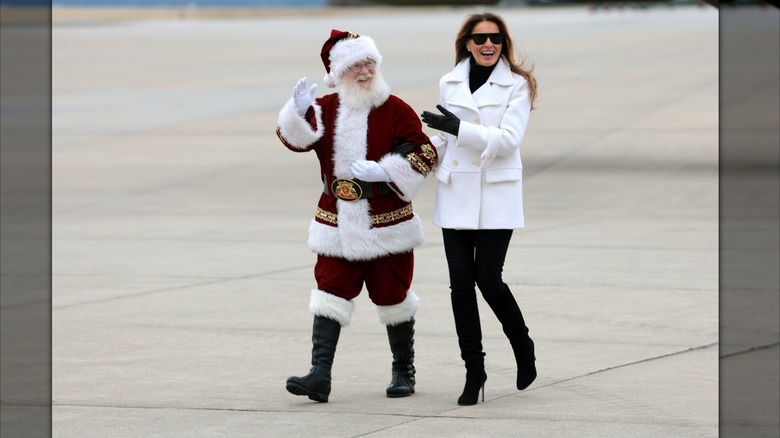Melania Trump walking wth Santa Claus in a black and white outfit