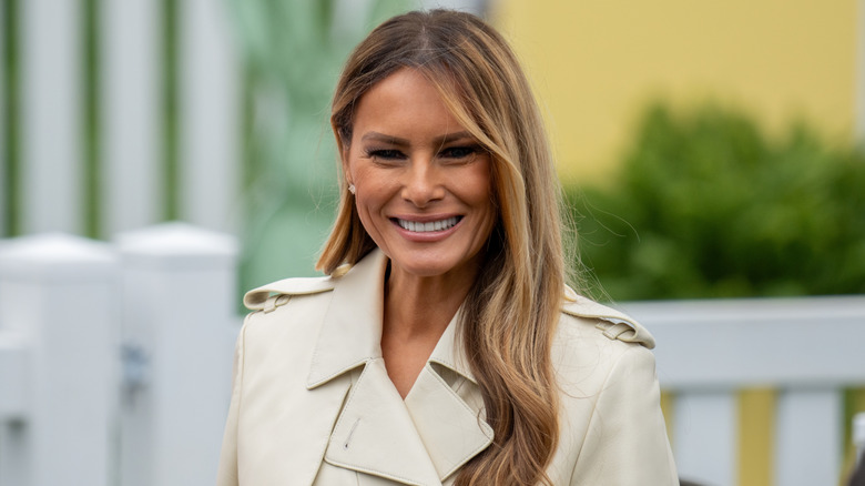 First lady Melania Trump smiling in a tan jacket