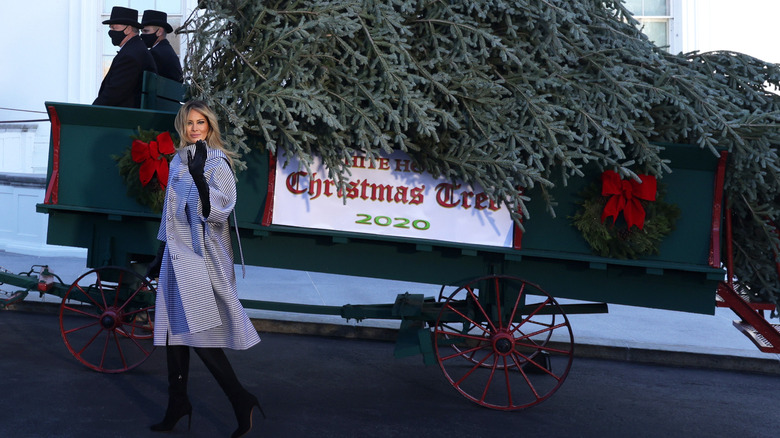 Melania Trump in a grey coat with the Christmas tree wagon