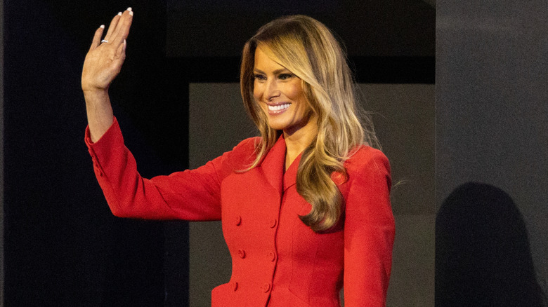 Melania Trump waving from stage in a red suit