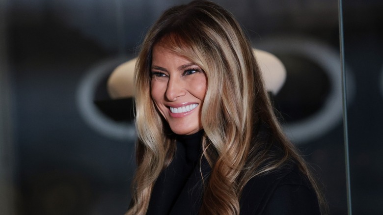 Melania Trump smiling in front of a black background