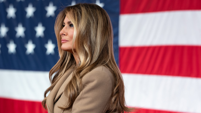 Melania Trump in side profile in front of an American flag