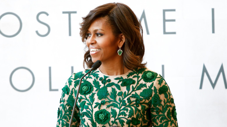 Michelle Obama in a green accented dress and speaking at a podium