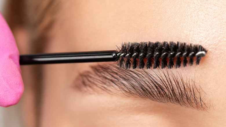 Makeup artist brushing client's brow