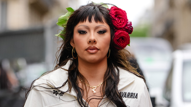 Woman with brown lip liner, thin eyebrows, and flowers in her hair