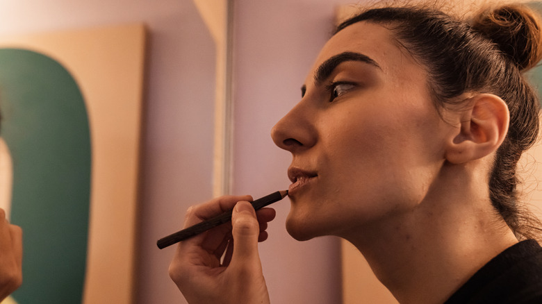 Woman applying brown lip liner