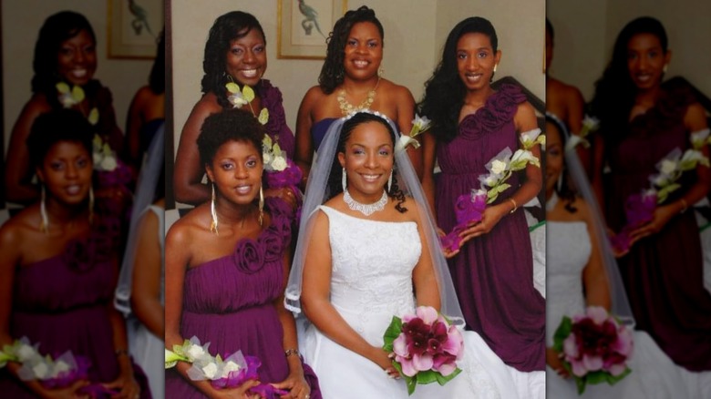 A bride in a one-shoulder gown with bridesmaids next to her in purple dresses