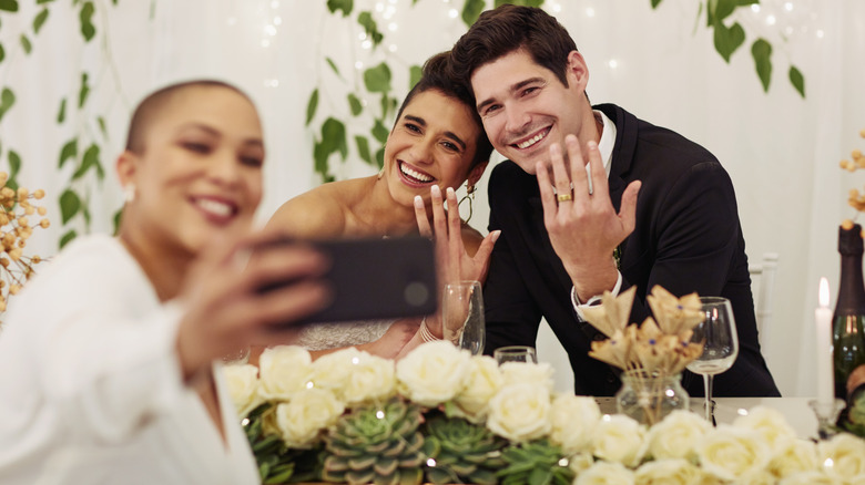 Wedding couple flashing piece signs and duck lips while holding up a phone for a selfie