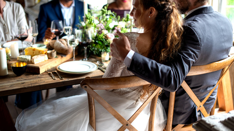 Newlyweds embracing at rustic table