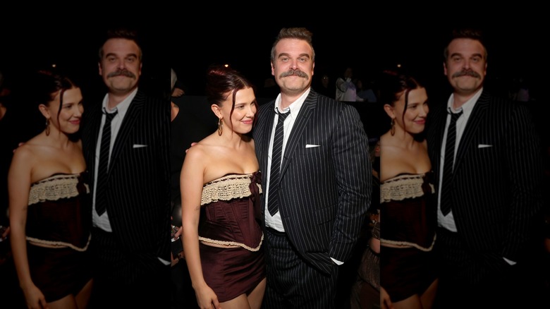 Millie Bobby Brown posing with David Harbour while wearing a lace-trimed, corset-style top