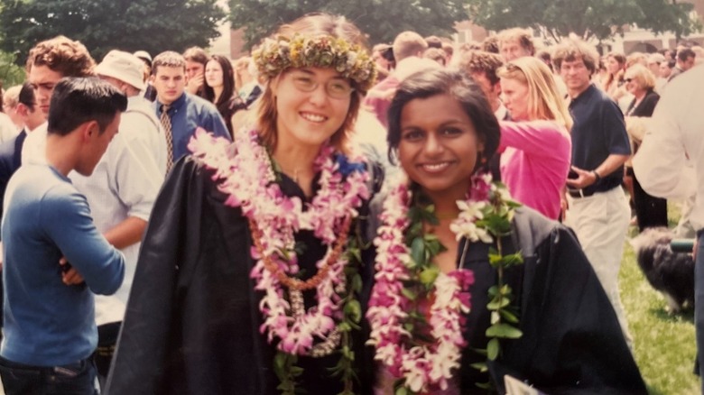 Mindy Kaling smiling in a black gown next to a friend on her college graduation day