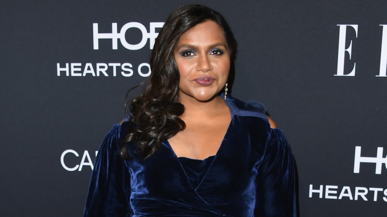Mindy Kaling on the red carpet in 2018 in a blue dress in front of a black background