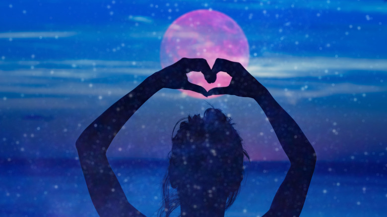 woman making heart over moon