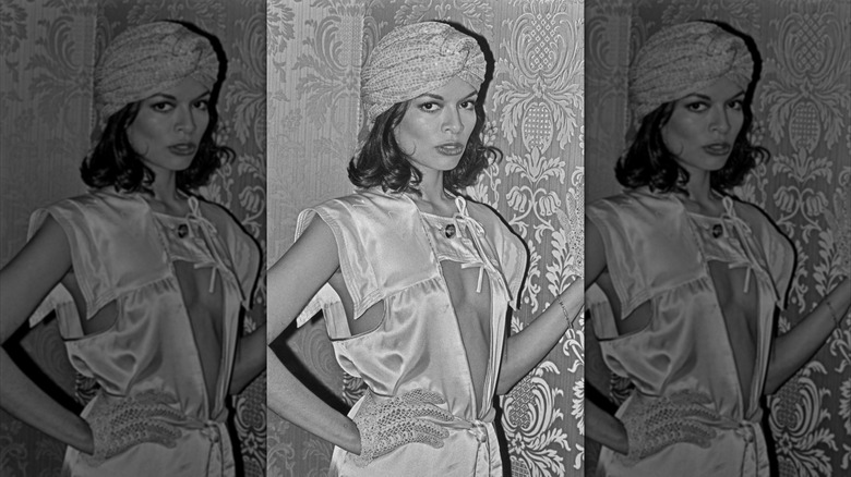 Bianca Jagger in a turban and a white dress with cutouts at an event