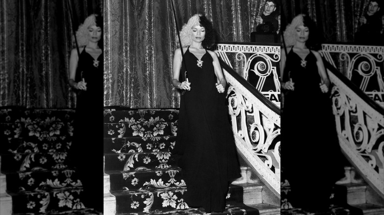 Bianca Jagger in a black and white wig with a cane and a black dress at a ball