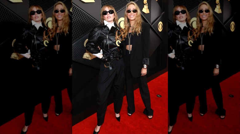 Miley Cyrus wearing a bulky leather jacket while posing with her mother Tish Cyrus